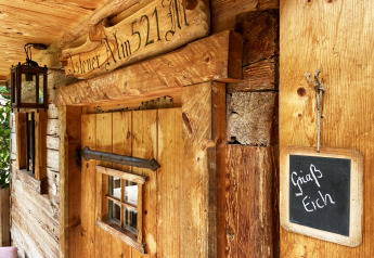 Chalet rustico chiamato 'Alm 521' con lanterna e lavagna 'Griaß Eich' sulla parete di legno in Germania.