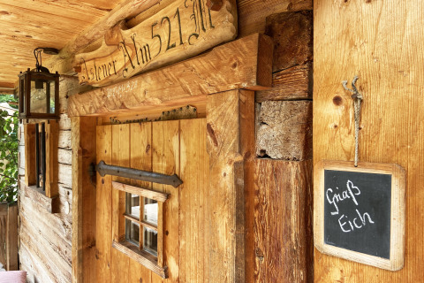 Berghut 'Alm 521' met houten deur, lantaarn, en bordje 'Griaß Eich' op de wand in Duitsland.