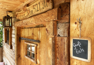 Berghut 'Alm 521' met houten deur, lantaarn, en bordje 'Griaß Eich' op de wand in Duitsland.