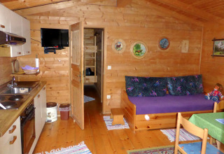 Interior view of Steingaden chalet in Germany showing wood walls, compact kitchen, and sofa area.