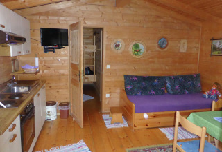 Interior view of Steingaden chalet in Germany showing wood walls, compact kitchen, and sofa area.