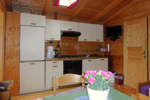 Cozy kitchen inside a chalet in Steingaden, Germany, with wooden walls, appliances, and a dining table.