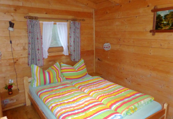 Camera da letto in legno allo chalet Steingaden in Germania con biancheria da letto colorata e tende.