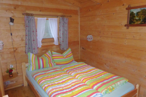 Cozy wooden bedroom at chalet Steingaden in Germany, featuring colorful striped bedding and curtains.