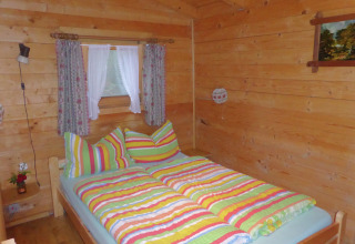 Cozy wooden bedroom at chalet Steingaden in Germany, featuring colorful striped bedding and curtains.