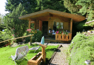 A cozy wooden chalet named Steingaden in Germany, surrounded by lush greenery and colorful flowers.