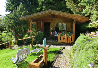A cozy wooden chalet named Steingaden in Germany, surrounded by lush greenery and colorful flowers.