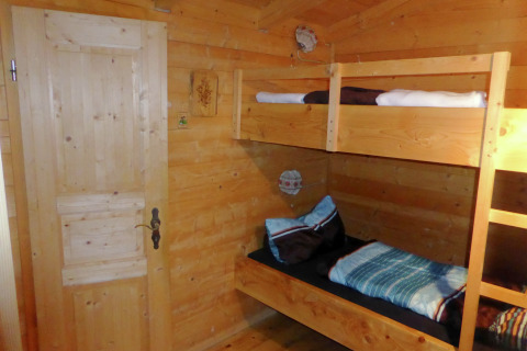 Wooden room with bunk beds in Chalet Steingaden, Germany, cozy interior and warm natural lighting.