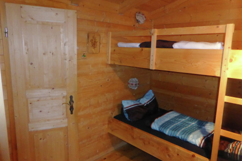 Wooden room with bunk beds in Chalet Steingaden, Germany, cozy interior and warm natural lighting.