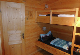 Wooden room with bunk beds in Chalet Steingaden, Germany, cozy interior and warm natural lighting.