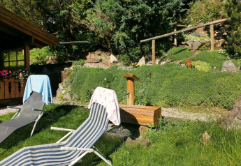 Area esterna allo chalet Steingaden in Germania con sdraio, asciugamani e un rigoglioso giardino verde.