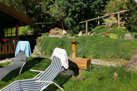Outdoor area at chalet Steingaden in Germany with deck chairs, towels, and a lush green garden.