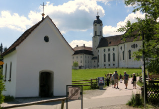 Photo of the Steingaden chalet and church in Germany with visitors walking on a sunny day.
