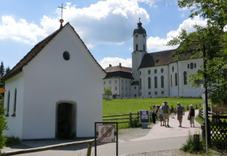 Photo of the Steingaden chalet and church in Germany with visitors walking on a sunny day.