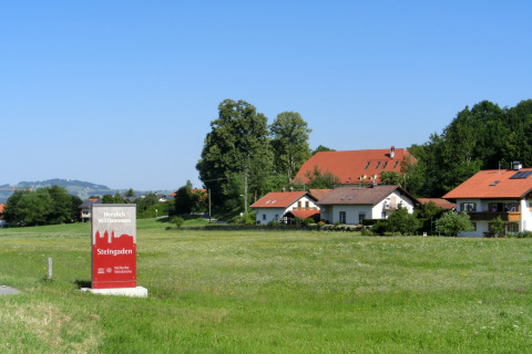 Steingaden chalet in Germany, charming houses with red roofs and a welcoming sign in a green countryside.