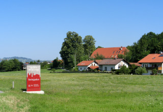 Steingaden chalet in Germany, charming houses with red roofs and a welcoming sign in a green countryside.