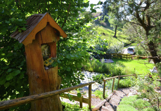 View of a lush garden at Chalet Steingaden in Germany, featuring a wooden figure and greenery.