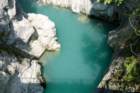 Photo of clear turquoise water surrounded by rocky cliffs at Chalet Steingaden in Germany, sunny day.