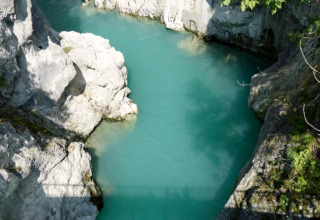 Photo of clear turquoise water surrounded by rocky cliffs at Chalet Steingaden in Germany, sunny day.