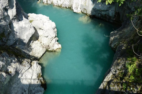Photo of clear turquoise water surrounded by rocky cliffs at Chalet Steingaden in Germany, sunny day.