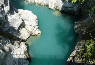 Photo of clear turquoise water surrounded by rocky cliffs at Chalet Steingaden in Germany, sunny day.