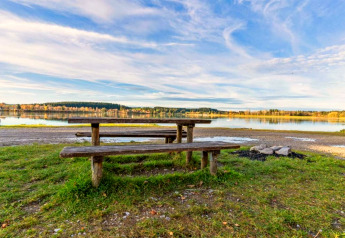 Tavolo da picnic e panche vicino a un lago presso lo chalet Steingaden in Germania, natura tranquilla.