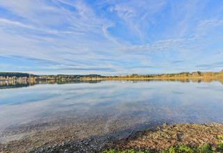 Tranquil lake view with clear water and blue sky, seen from Chalet Steingaden in Germany.