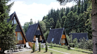 Vakantiehuisjes in A-vorm bij Holiday park Jägerwiesen 1, gelegen tussen groene bomen en natuur nabij een bos.