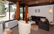 Living area at Holiday park «Jägerwiesen 1» in Germany with sofa, armchair, TV, and large windows.
