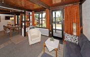 Living room with wood ceiling, large windows, and dining area at Holiday park Jägerwiesen 1, Germany.