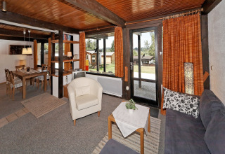 Living room with wood ceiling, large windows, and dining area at Holiday park Jägerwiesen 1, Germany.