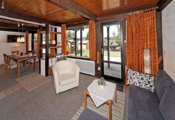Living room with wood ceiling, large windows, and dining area at Holiday park Jägerwiesen 1, Germany.