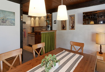 Dining room at Holiday park Jägerwiesen 1 in Germany with wooden furniture, hanging lamps, and kitchen view.