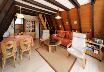 Cozy living room at Holiday park Jägerwiesen 1 in Germany, featuring wood walls, sofa, and dining area.