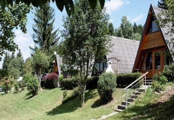 A-frame lodges and greenery at Holiday park «Jägerwiesen 1» in Germany on a bright sunny day.