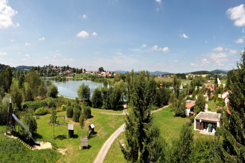 Panoramablick auf See, Ferienpark und Grünflächen bei Holiday park Jägerwiesen 1 unter blauem Himmel.
