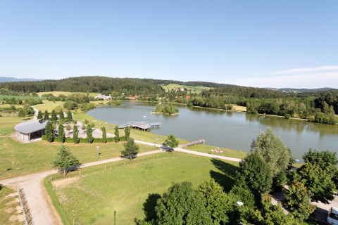 Udsigt over Holiday park «Jägerwiesen 1» i Tyskland med sø, grønne marker, træer og badebro.