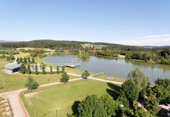 A view of Holiday park «Jägerwiesen 1» in Germany, showing a lake, pier, green lawns and trees.