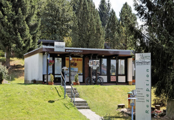 Reception building of Holiday Park Jägerwiesen 1 in Germany surrounded by green trees and a lawn.