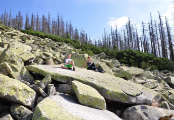 Two people sitting on large rocks at Holiday Park Jägerwiesen 1, Germany, with trees in the background.