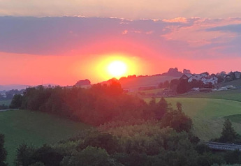 Sunset over a green countryside seen from Holiday park «Jägerwiesen 1» in Germany, with distant houses.