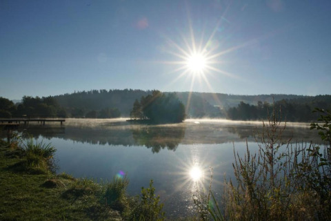 Sunrise over a calm lake at Holiday park «Jägerwiesen 1» in Germany with reflection and serene landscape.