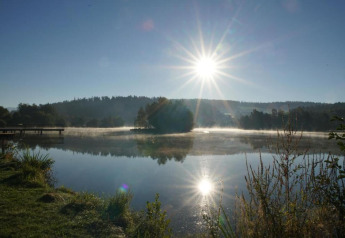 Sunrise over a calm lake at Holiday park «Jägerwiesen 1» in Germany with reflection and serene landscape.