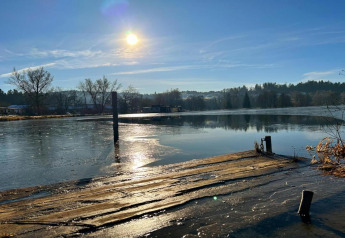 Sunny morning at a frozen lake and pier in Holiday park «Jägerwiesen 1», Germany, with winter landscape.