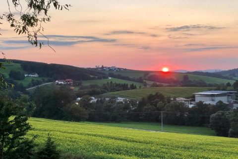 Sunset view over rolling green fields and village, taken from Holiday park Jägerwiesen 1 in Germany.