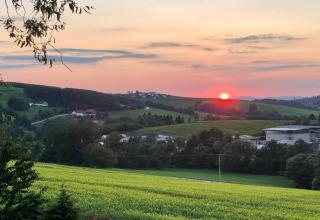 Sunset view over rolling green fields and village, taken from Holiday park Jägerwiesen 1 in Germany.