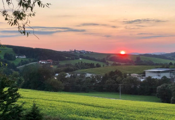 Sunset view over rolling green fields and village, taken from Holiday park Jägerwiesen 1 in Germany.