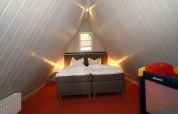 Schlafzimmer im Loftstil in einer Nurdachhaus-Lodge in Deutschland mit Bett und Kinderreisebett.