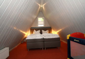 Camera mansardata nella lodge Nurdachhaus in Germania con letto matrimoniale e lettino per bambini.