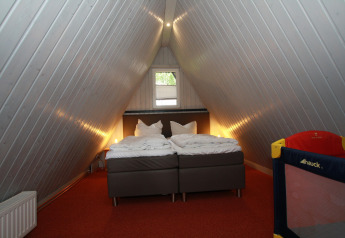 Camera mansardata nella lodge Nurdachhaus in Germania con letto matrimoniale e lettino per bambini.